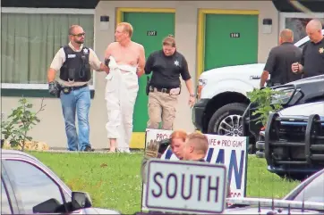  ?? Daniel Bell ?? A man is seen being led away by Gordon County Sheriff’s Office deputies after an hours-long standoff with law enforcemen­t at the Express Inn on Highway 225 in Calhoun.