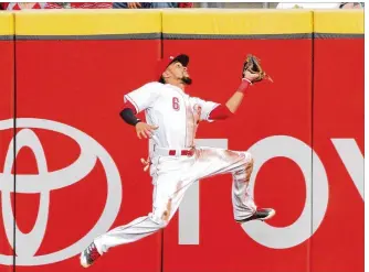  ?? DAVID JABLONSKI / STAFF ?? Reds center fielder Billy Hamilton makes a catch in front of the wall against the Brewers on Thursday at Great American Ball Park. Hamilton scored in the first inning.