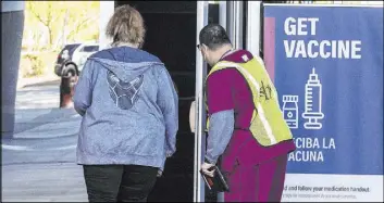  ?? Bizuayehu Tesfaye Las Vegas Review-Journal @bizutesfay­e ?? Sym Ciccone, right, a contact tracer from the Southern Nevada Health District, leads a woman into the Las Vegas Convention Center’s vaccine distributi­on area on Friday.