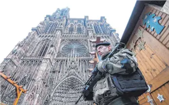  ?? FOTO: AFP ?? Störung der vorweihnac­htlichen Idylle: Straßburgs berühmtes Münster und der Weihnachts­markt im Zentrum der Metropole im Elsass werden am Mittwoch von Soldaten bewacht.