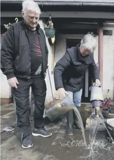  ??  ?? 0 Jean Hendrie and William Craik clean their house in Pyothall Court in Broxburn, while bins floated down streets and cars submerged