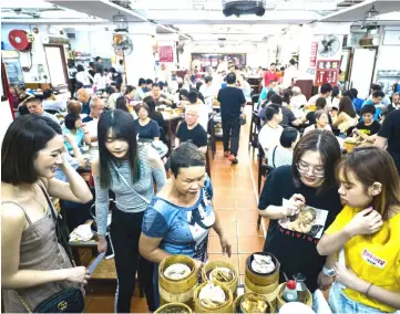  ??  ?? In this photo taken on Aug 7, diners stand around a trolley of bamboo steamers containing freshly steamed dim sum dishes at the Lin Heung Tea House in Hong Kong.