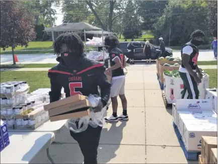  ?? PHOTOS COURTESY OF DANA CITO ?? The senior football captains at Michigan Collegiate helped distribute food to the needy. Distributi­on took place at their own school in Warren and at Conner Creek Academy East in Roseville. Coach John Guth was a key part of the effort. Gleaners provided the food.