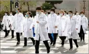  ?? PTI ?? Medical workers from Beijing walk near a park during a day off as the city of Wuhan slowly loosens up ahead of a lifting of the two month long lockdown in central China's Hubei province on Sunday