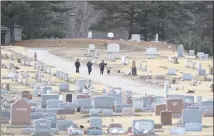  ??  ?? Police officers walk through Wooster Cemetery near Danbury Hospital after a shooting in January.