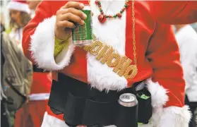  ??  ?? Top: Esme Galarza of Fresno joins friends in Christmas songs as SantaCon gets under way in Union Square last year. Above: Jaime Madriz of Santa Rosa has a beer before the crowd sets off to visit a series of bars.