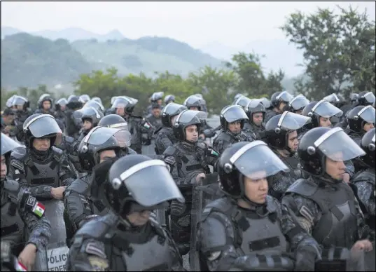  ?? Rebecca Blackwell The Associated Press ?? Mexican federal police in riot gear block a highway Saturday to keep a thousands-strong caravan of Central American migrants from advancing toward the U.S. border outside Arriaga, Mexico.