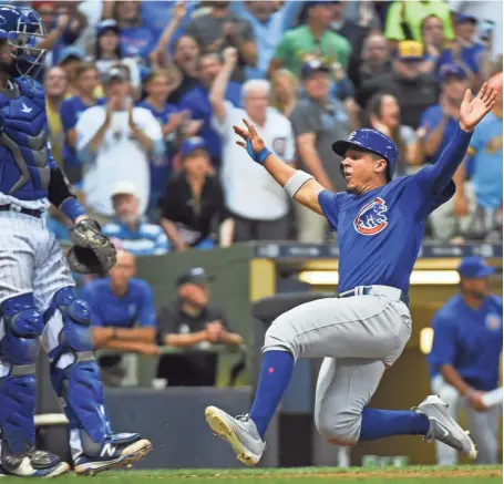  ?? BENNY SIEU / USA TODAY SPORTS ?? Cubs leftfielde­r Jon Jay scores in front of Brewers catcher Manny Pina in the seventh inning to tie the game, 1-1, at Miller Park on Saturday night.