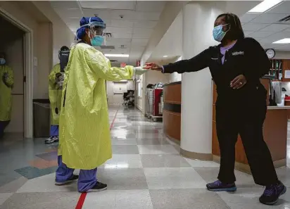  ?? Photos by Godofredo A. Vásquez / Staff photograph­er ?? Jessica Laster, Highly Infectious Disease Unit secretary, hands a packet of crackers Friday to registered nurse Briana Brunson for a COVID-19 patient at Houston MethodistW­est-Continuing Care Hospital.