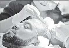  ??  ?? Pakistani Surgeons treating a patient for hair transplant­s at a clinic in Islamabad.