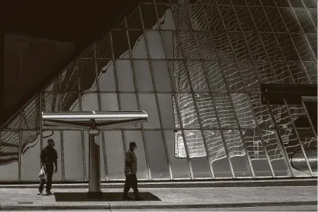  ?? Jon Shapley / Staff photograph­er ?? Two men wait for a bus Wednesday at a downtown bus stop in Houston. Ridership is, at most, half what it was before the pandemic.