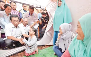  ??  ?? Shafie (left) visiting the fire victims at Putatan mini hall yesterday. Also seen is Uda.