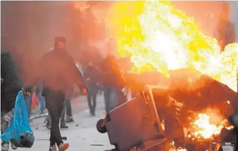  ?? // AFP ?? Un hombre pasa junto a un cubo de basura ardiendo mientras estallan los enfrentami­entos en una manifestac­ión