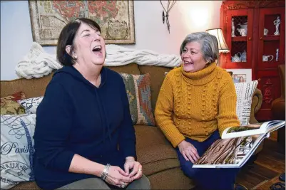  ?? HYOSUB SHIN / HYOSUB.SHIN@AJC.COM ?? Toni Appling (left) laughs with her friend Mary Schrepfer as they look at a dog coffee table book together at Appling’s home in Johns Creek. Facing kidney failure, Appling now needs someone to save her. Schrepfer is going through the testing process. And while she and Toni don’t have compatible blood types, Schrepfer is offering to be part of a paired kidney exchange.