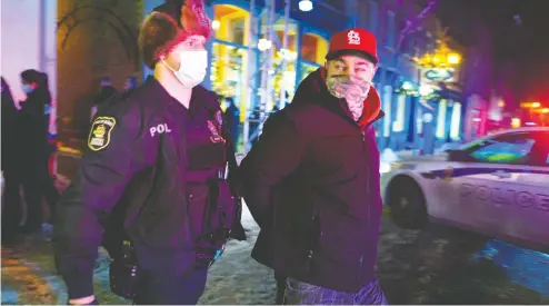  ?? JACQUES BOISSINOT / THE CANADIAN PRESS ?? Police arrest a Quebec City resident out after 8 p.m. as a curfew began in the province of Quebec on Jan. 9 in an effort
to help curb the spread of COVID-19. A handful of demonstrat­ors walked downtown to protest the curfew.