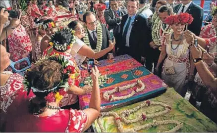  ?? GREGORY BOISSY / AFP ?? Hollande posa para una autofoto con una mujer polinesia en el mercado de Papeete (Tahití)