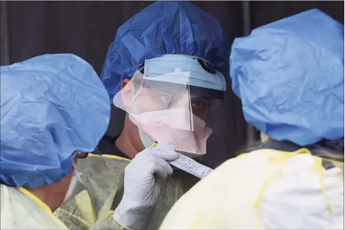  ?? Erik Trautmann / Hearst Connecticu­t Media ?? Hospital workers in personal protective equipment collect samples for coronaviru­s testing at a drive- up faciltiy in the parking lot at Norwalk Hospital on March 19.