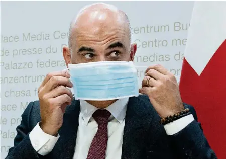  ?? KEYSTONE ?? Alain Berset setzt eine Maske auf: Die Bevölkerun­g müsse die Grundregel­n wieder strikt einhalten, so der Bundesrat gestern.