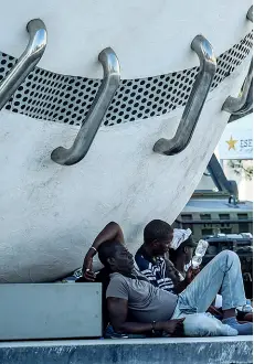  ?? (foto Furlan) ?? La giornata Sopra, nella foto grande: un gruppo di migranti riposa sotto la «Mela» di Pistoletto in piazza Duca d’Aosta. A sinistra: via Sammartini e le aiuole della Centrale