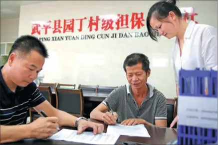  ?? PROVIDED TO CHINA DAILY ?? (middle) signs a loan agreement with the bonding cooperativ­e in Wuping county, Fujian province.