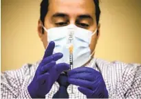  ??  ?? Pharmacy Operations Manager Eddie Isaac prepares a syringe for a COVID-19 dose at the Scripps Memorial Hospital La Jolla vaccinatio­n site on Monday.