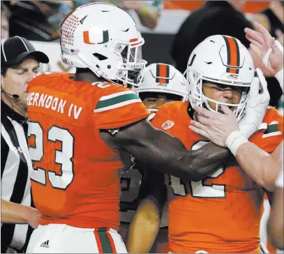  ?? Lynne Sladky ?? The Associated Press Miami quarterbac­k Malik Rosier is congratula­ted by tight end Christophe­r Herndon IV (23) after running for a touchdown in the first half of the then-no. 7 Hurricanes’ 41-8 victory over then-no. 3 Notre Dame on Saturday night in...