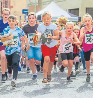  ??  ?? Children vie for top spot carrying their bags of tatties.