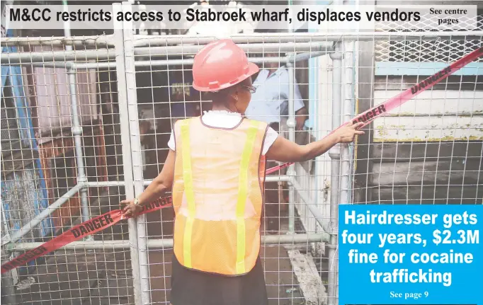  ?? (Photo by Terrence Thompson) ?? A city occupation­al health and safety officer placing tape on one of the barricades restrictin­g access to the Stabroek Market Wharf.