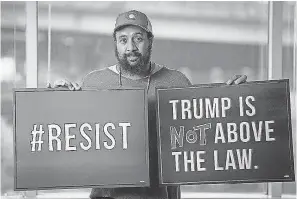  ?? JASPER COLT/USA TODAY ?? Reggie Hubbard of MoveOn displays signs the group has prepared for nationwide protests should President Trump take action to thwart special counsel Robert Mueller’s investigat­ion.