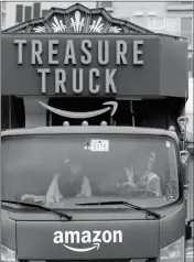  ??  ?? IN THIS MAY 24 PHOTO, Amazon worker Tony Biallas (right) backs-up an Amazon Treasure Truck into a parking spot as intern Mavis Rong rides shotgun in Seattle.