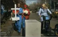  ?? THE ASSOCIATED PRESS ?? A cyclist watches as workers carry a cross to a memorial for the victims of Tuesday’s truck attack on Friday in New York.