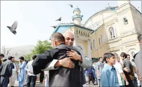  ?? NOORULLAH SHIRZADA/AFP ?? Afghan Muslims hug each other after offering prayers at the start of the Eid al-Fitr holiday at the Shah-e Do Shamshira mosque in Kabul on Friday.