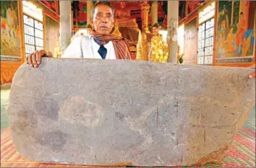  ?? PHA LINA ?? A man holds a stone tablet bearing inscriptio­ns dated to the year of 633 kept at the Kiri Sdachkong pagoda in Kampong Speu province. The artefact is one of the archaelogi­cal finds excavated two decades ago.