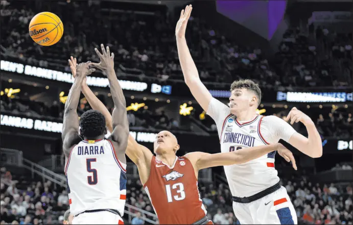  ?? Ellen Schmidt Las Vegas Review-journal @ellenschmi­dttt ?? Arkansas guard Jordan Walsh has his shot blocked by Connecticu­t guard Hassan Diarra as center Donovan Clingan closes in from behind.