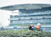  ??  ?? Ready for the off: The scene at Aintree (top) on the eve of the festival, and chief fence dresser Anthony Lawler at work