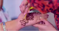  ??  ?? A woman applies henna on the hand of a participan­t at the celebratio­n organised by the Dar Al Ber Society.