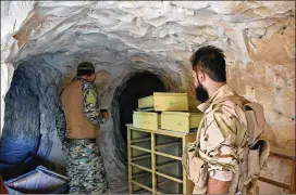  ?? SYRIAN ARAB NEWS AGENCY ?? Syrian troops and pro-government gunmen stand inside a cave Saturday that they seized from Islamic State militants in the eastern city of Deir el-Zour, Syria. The city has been divided into government- and IS-controlled parts since 2015.