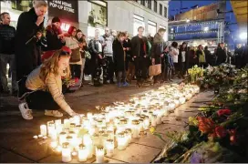  ?? MARKUS SCHREIBER/ AP ?? A woman places a candle in front of the department store Ahlens on Sunday in Stockholm, where a truck was driven into pedestrian­s Friday.