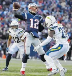  ?? AP PHOTO/ELISE AMENDOLA ?? New England Patriots quarterbac­k Tom Brady passes between Los Angeles Chargers linebacker Uchenna Nwosu (42) and defensive back Desmond King during Sunday’s game in Foxborough, Mass.
