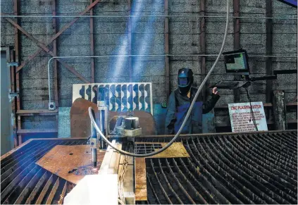  ?? Michael Ciaglo photos / Houston Chronicle ?? Developmen­t director Lauren Caldarera runs the plasma cutter at TX/RX, a space for people to build, fabricate and create.