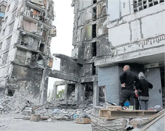  ?? AP ?? Desastre. Vecinos observan partes de un edificio en ruinas de la ciudad portuaria de Mariúpol sometida a un persistent­e ataque de la artillería.