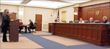  ??  ?? Colonnade Director Lora Ogden (standing at the lectern) discusses the details of a bid for new banquet chairs during the Dec. 1 Board of Commission­er’s meeting.