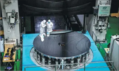  ?? XU CHANG / XINHUA ?? Scientific researcher­s check the condition of their large silicon carbide mirror in Changchun, Jilin province, on Tuesday. The high-precision mirror, 4 meters in diameter, is the latest achievemen­t of a national scientific equipment project.