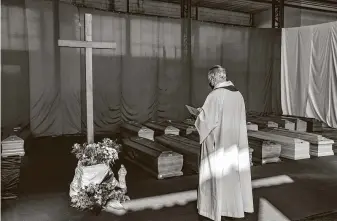  ?? Francesca Volpi / Bloomberg ?? A priest in northern Italy blesses coffins containing virus victims. Italy, by virtue of its early and widespread exposure to the virus, has an opportunit­y to gain insight into how the virus works.