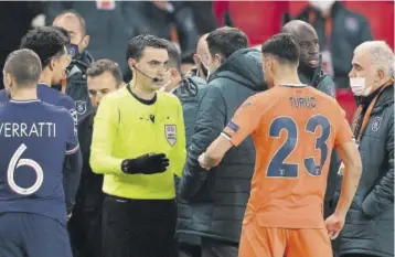  ?? (Photos: AFP) ?? Romanian referee Ovidiu Hategan (in yellow) talks to Istanbul Basaksehir’s staff members and Istanbul Basaksehir’s French forward Demba Ba (second right) after the game was suspended amid allegation­s of racism by one of the match officials during the UEFA Champions League Group H football match between Paris Saint-germain (PSG) and Istanbul Basaksehir FK at the Parc des Princes stadium in Paris yesterday.
