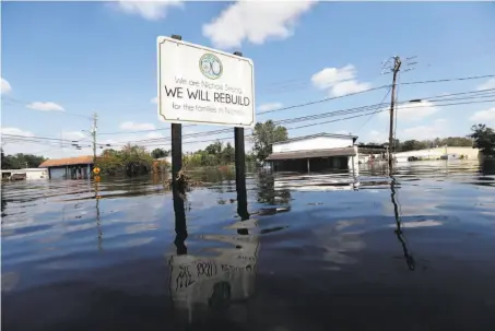  ?? Gerald Herbert / Associated Press ?? A sign in flooded Nichols, S.C., commemorat­es the rebuilding of the town after it was hit by Hurricane Matthew in 2016.