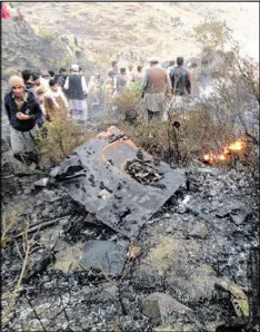  ?? XINHUA / ZUMA PRESS / TNS ?? Locals gather at a plane crash site Wednesday. A Pakistan Internatio­nal Airlines (PIA) plane with at least 48 people on board crashed in the country’s northern Havelian area on Wednesday, officials said. No survivors were reported.