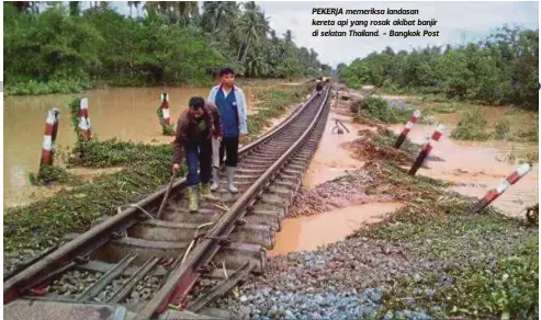  ??  ?? PEKERJA memeriksa landasan kereta api yang rosak akibat banjir di selatan Thailand. - Bangkok Post