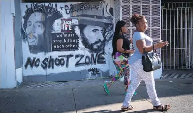  ?? MANDEL NGAN / AGENCE FRANCE-PRESSE ?? Women walk past a sign with a message to end gun violence in Baltimore on Wednesday.