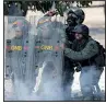  ??  ?? AP/ARIANA CUBILLOS National Guardsmen take cover Wednesday as protesters advance on the Carlota air base in Caracas.